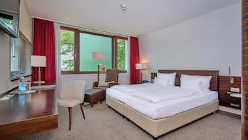 A hotel room with a bed, desk, chair, and two bedside tables.