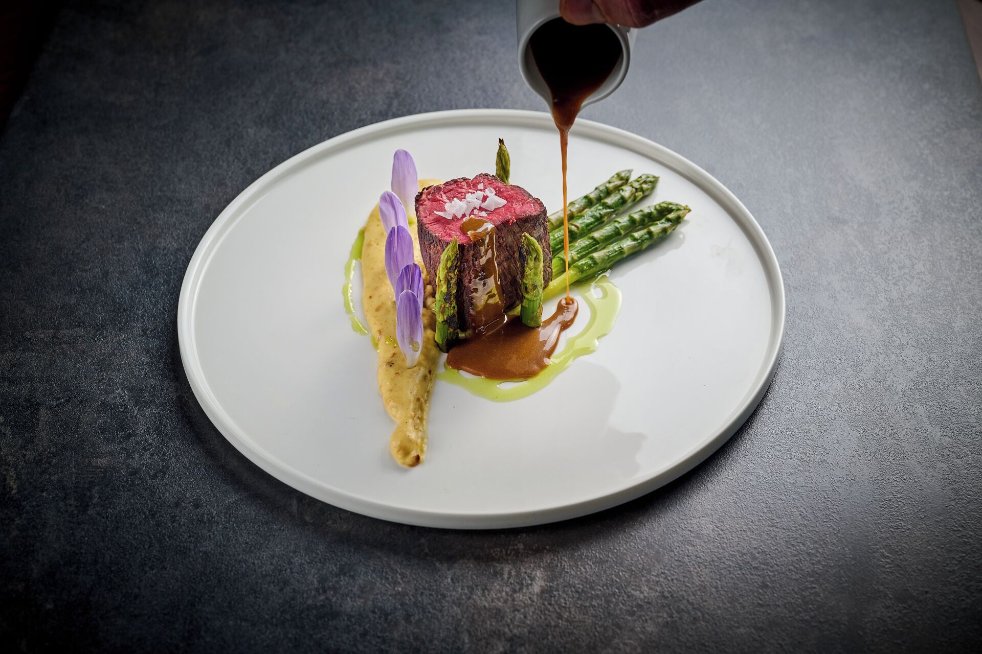 A plate with a steak, asparagus, and sauce.