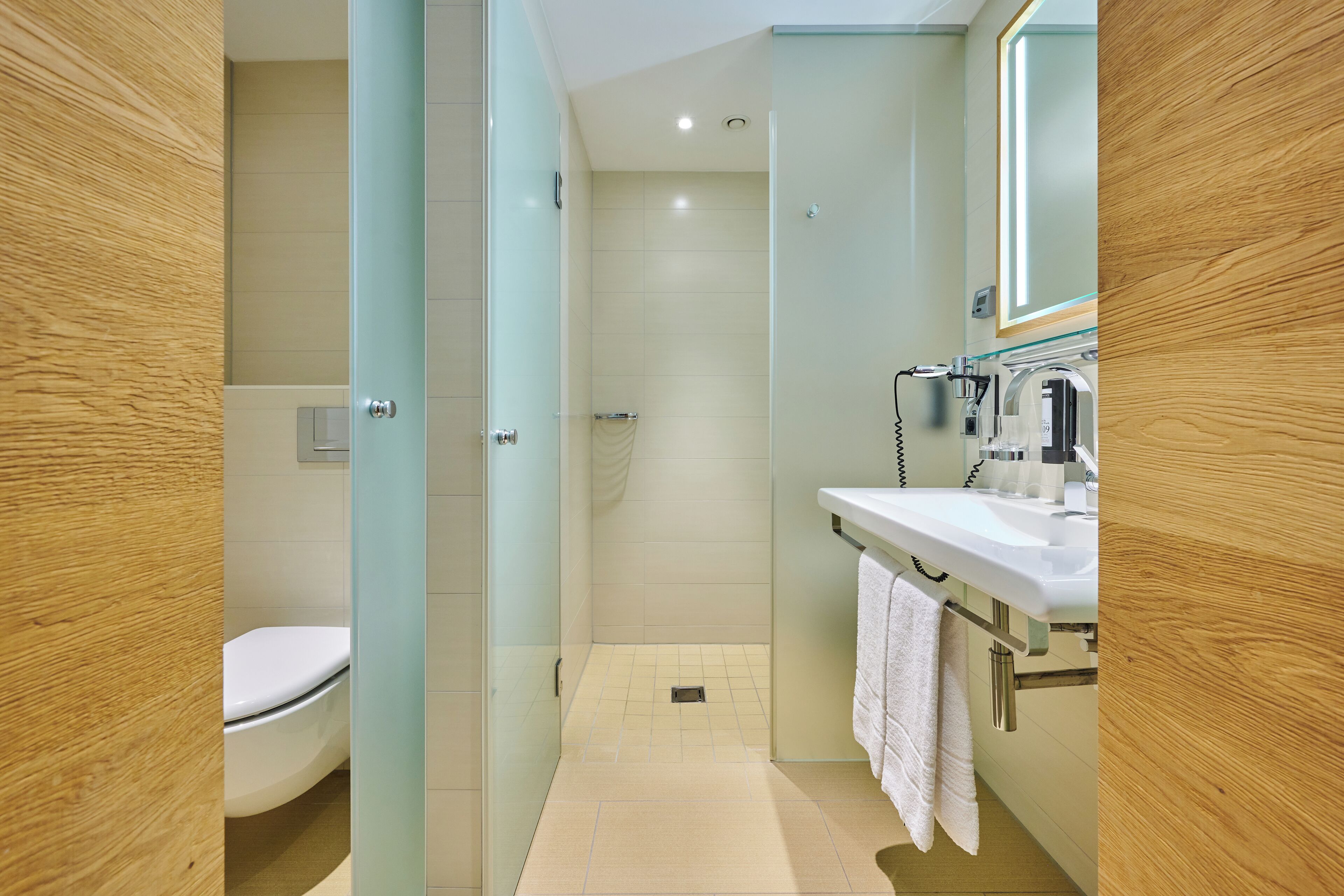 Un baño moderno con cabina de ducha de vidrio, un lavamanos blanco y un inodoro.