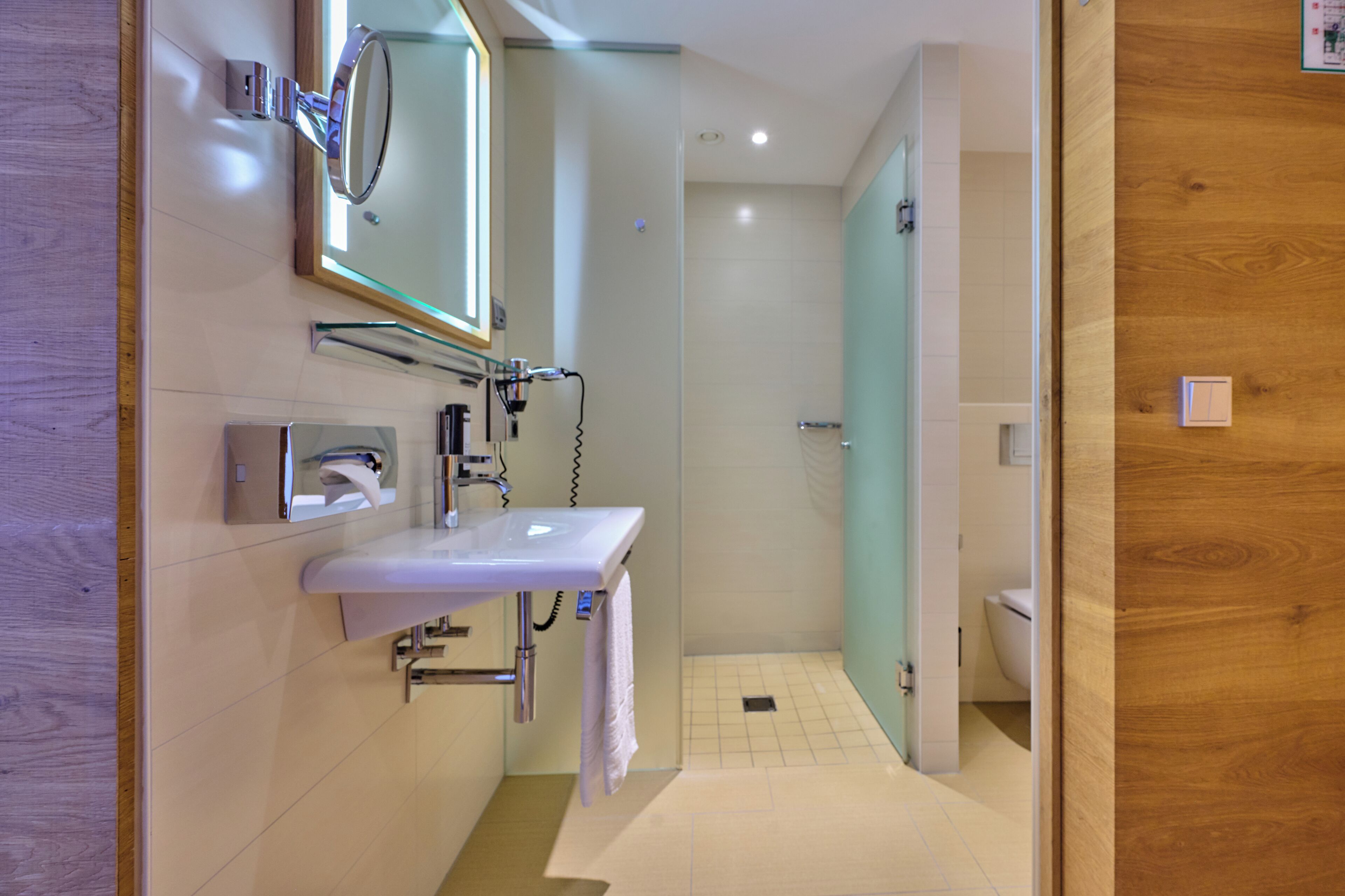 A modern bathroom with a white sink, mirror, and shower.