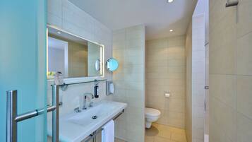 Un baño moderno con cabina de ducha de vidrio, un lavabo blanco y un inodoro.