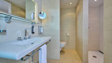 A modern bathroom with a glass shower enclosure, a white sink with a mirror, and a toilet.