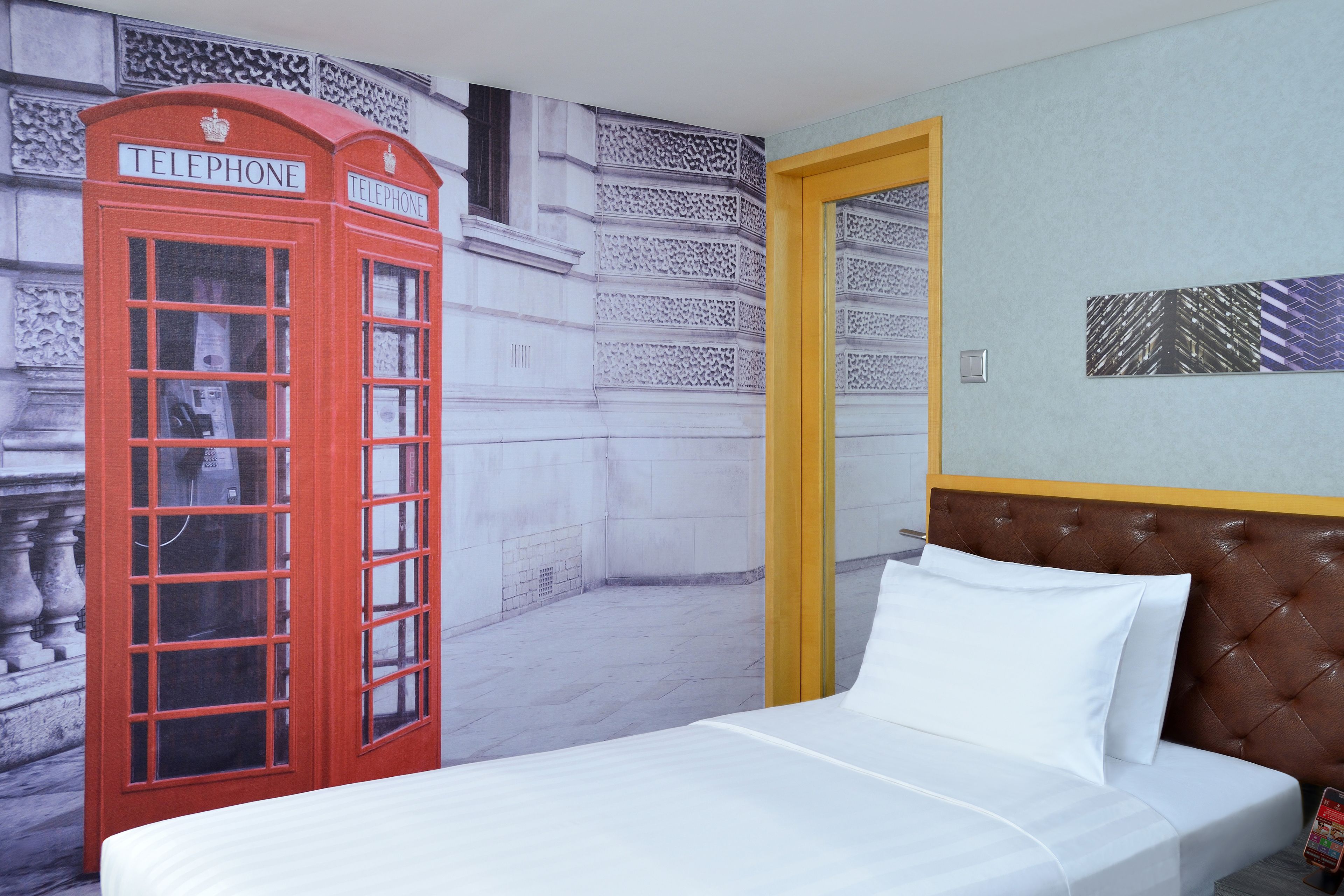 A room with a bed, a red telephone booth, and a door.
