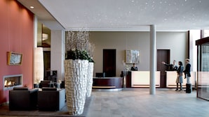 A spacious lobby with a reception desk, seating area, and a decorative plant centerpiece. - A-ROSA Travemünde (Lübeck)