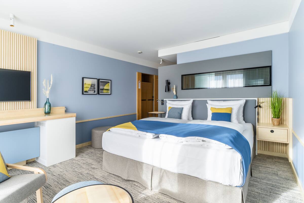 Una habitación de hotel moderna con una cama, una mesita de noche y un escritorio con silla.