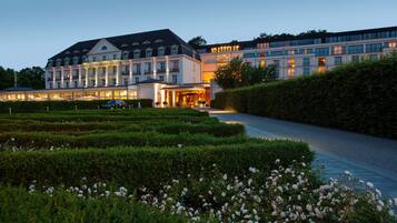 Ein Hotel mit einer repräsentativen Fassade, gepflegten Gärten und einem ordentlich angelegten Weg zum Eingang.