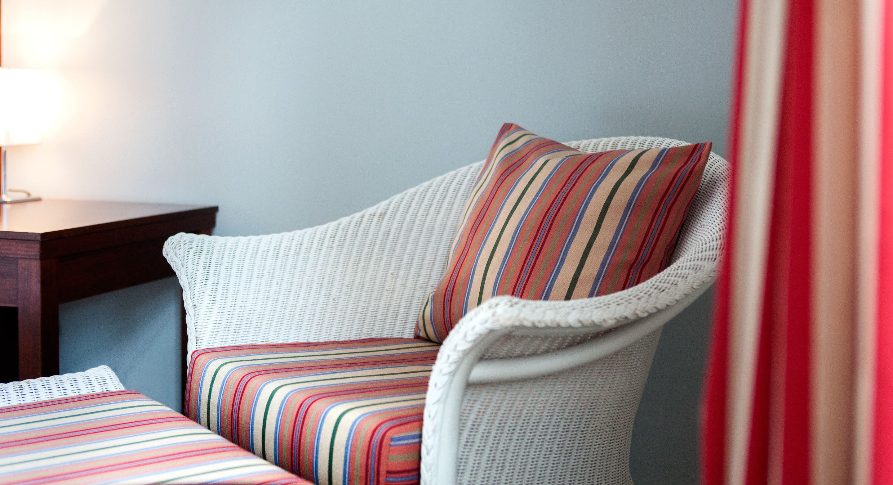 Une chaise en osier avec un coussin à rayures et un couvre-lit assorti, également à rayures.