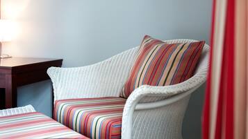 Une chaise en osier avec un coussin à rayures et un couvre-lit assorti, également à rayures.