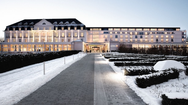 A large, modern hotel with a symmetrical facade, a central entrance, and a snow-covered garden. - A-ROSA Travemünde (Lübeck)