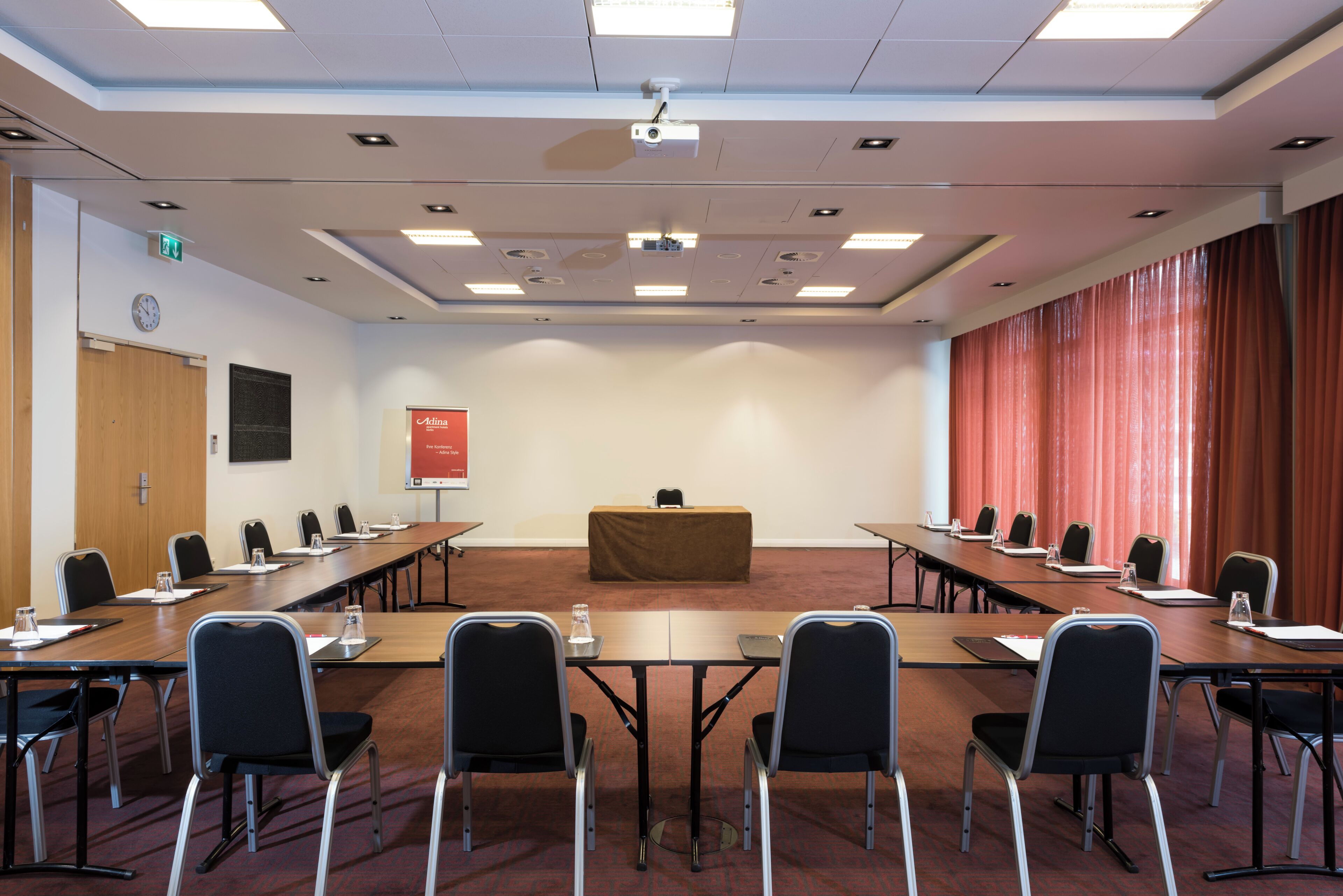 Une salle de conférence équipée d’une longue table, de chaises, d’un pupitre et d’un projecteur.