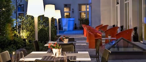 An outdoor dining area with tables, chairs, and ambient lighting.