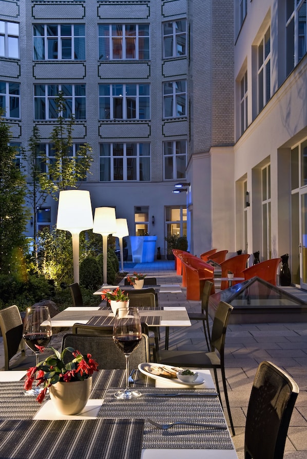An outdoor dining area with tables, chairs, and ambient lighting.