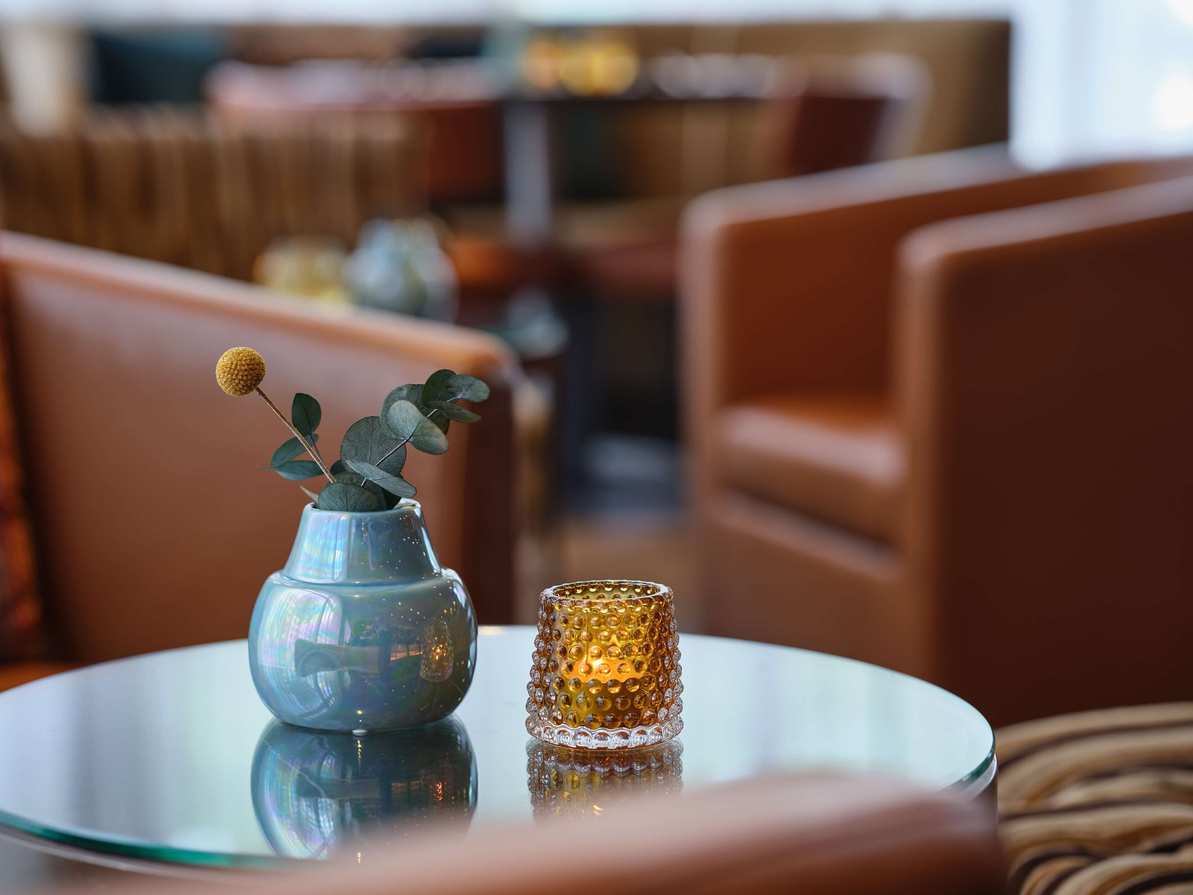 A glass table with a vase and a candle.