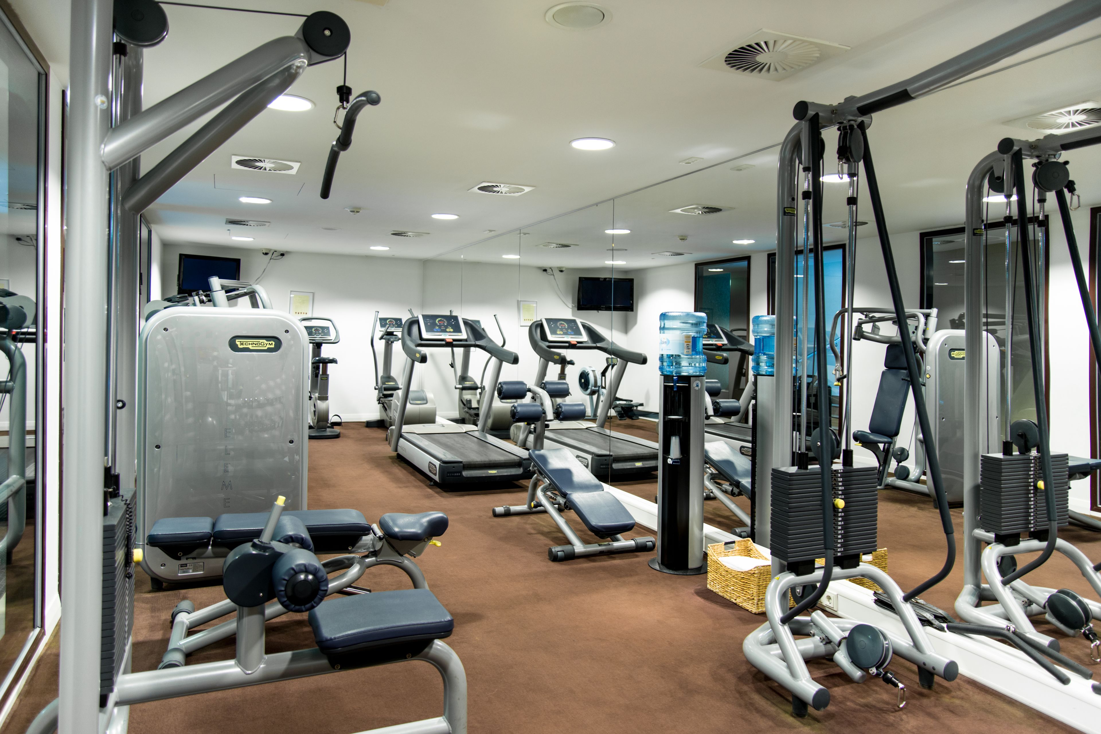 Un gimnasio con cintas de correr, elípticas y máquinas de pesas.
