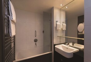 Un baño moderno con ducha envuelta en vidrio, un lavamanos blanco y un espejo grande.