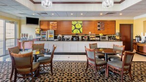 Un vestíbulo de hotel con comedor, cocina y televisor.