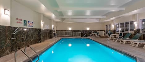 Une piscine intérieure dotée d’un espace de baignade bien délimité, de chaises longues et d’un plafond équipé d’un système d’éclairage encastré.