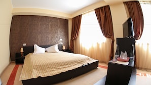 Une chambre d’hôtel moderne dotée d’un grand lit, d’une télévision à écran plat et d’un bureau avec une bouteille d’eau.