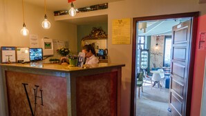 Un comptoir d’accueil d’hôtel avec un réceptionniste, un ordinateur et une horloge indiquant 8 h 40.