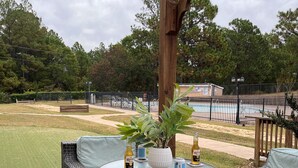 Une terrasse extérieure avec des meubles en osier et une table où sont disposées des bouteilles de bière.