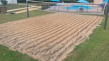 A volleyball court with a net, surrounded by a fence.