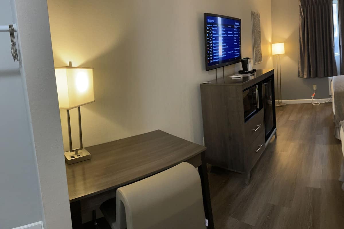 Una habitación de hotel con dos camas, un escritorio, un televisor y una lámpara.