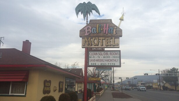 A motel sign with a palm tree and a bell, indicating a tropical theme. - Bali Hai Motel (Yakima)