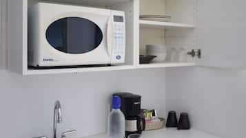 Una cocina con microondas blanco, un fregadero y una cafetera.