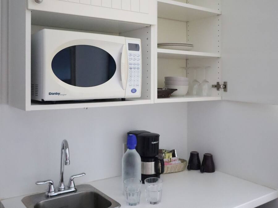 Una cocina con microondas blanco, un fregadero y una cafetera.