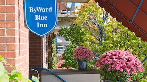 Une enseigne de l’hôtel ByWard Blue Inn, un bâtiment en briques et des plantes en pot ornées de fleurs.
