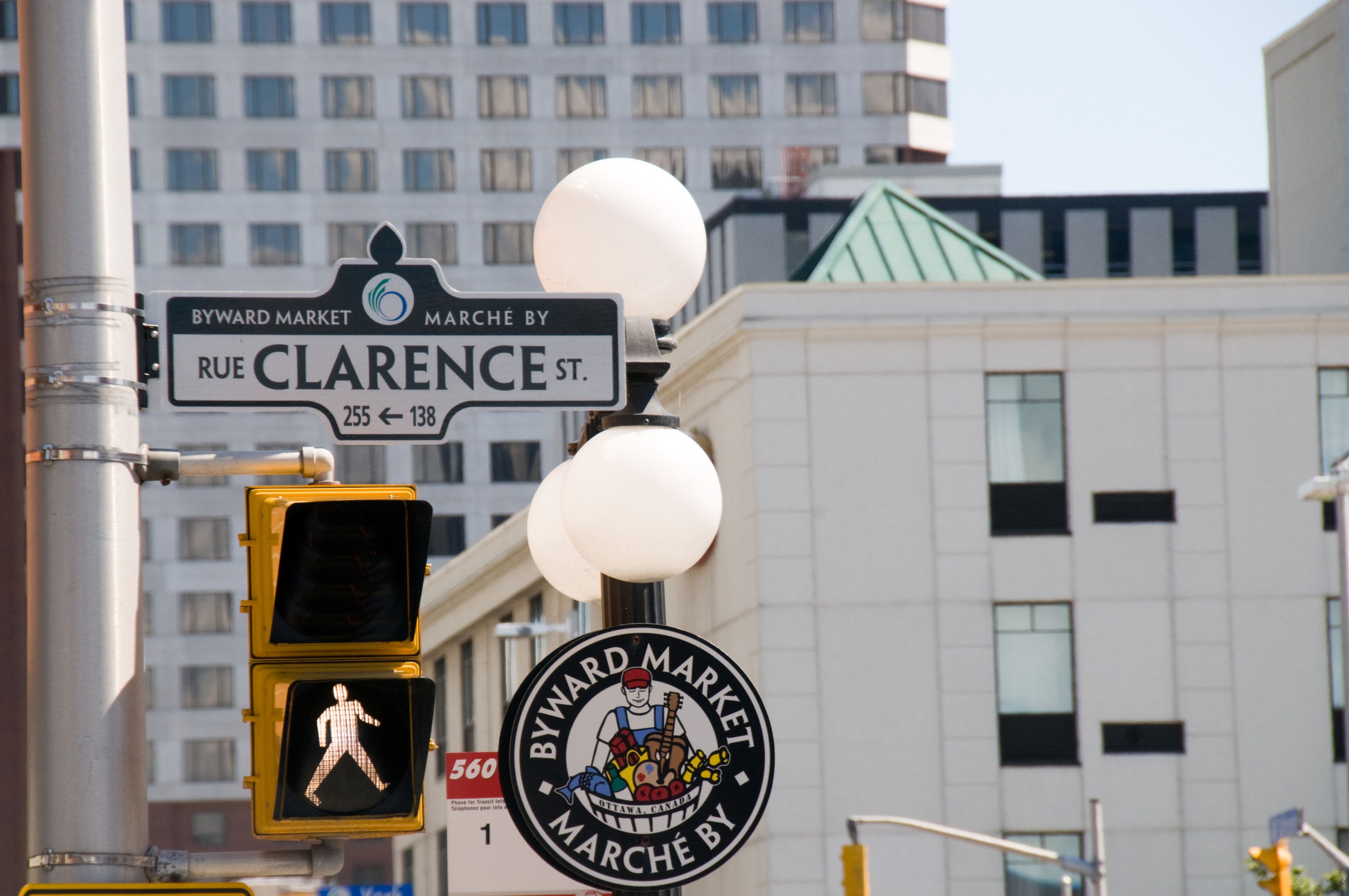 A street sign for Rue Clarence St. with a pedestrian crossing signal and a Byward Market sign.