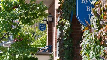 A ByWard Blue Inn sign with a brick building and greenery in the background.