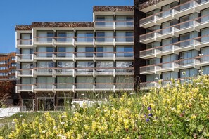 A multi-story hotel with balconies and a garden area in the foreground.