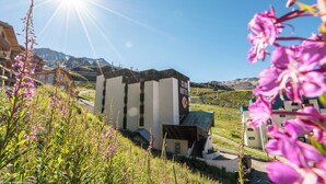 A hotel with a modern design, a mountain backdrop, and a clear sky. - Résidence Pierre & Vacances Val Thorens Le Gypaete (Les Belleville)