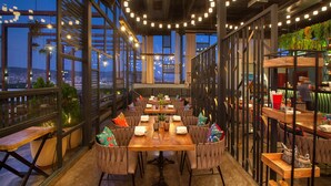 A modern restaurant with high ceilings, exposed beams, and large windows offering city views. - Lemon Tree Premier, Jaipur (Jaipur)