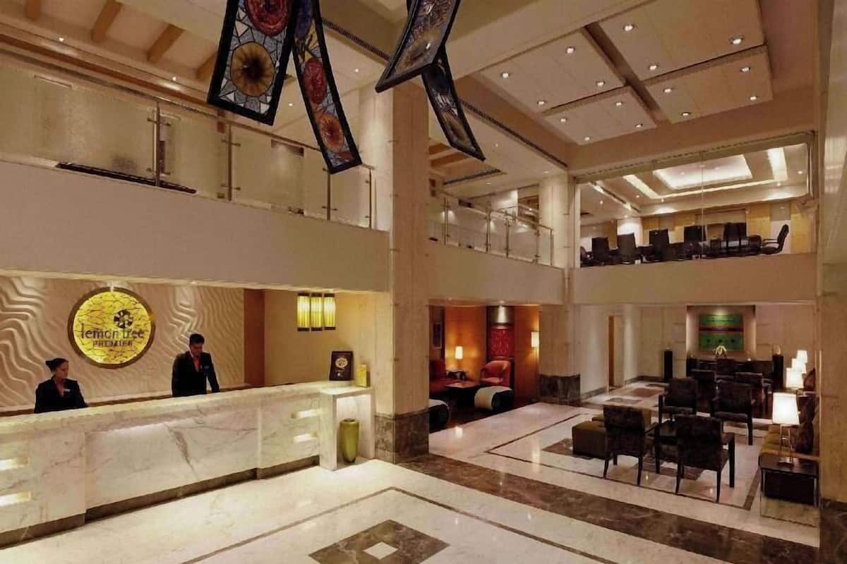 A hotel lobby with a reception desk, seating area, and a staircase.