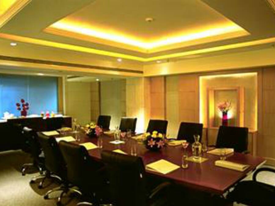 A conference room with a long table, chairs, and a small side table with a vase of flowers.