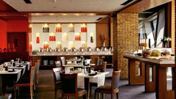 Un restaurant doté de nombreuses tables et chaises, d’un bar et d’un mur en briques.