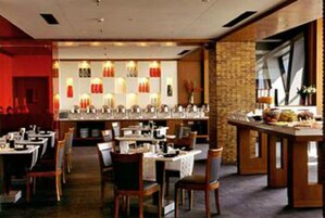 A restaurant with multiple tables and chairs, a bar area, and a brick wall.