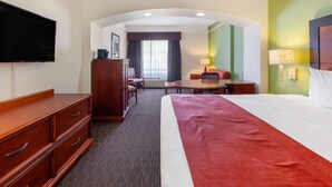 Ein Hotelzimmer mit einem großen Bett, einem Schreibtisch, einem Stuhl, einem Fernseher und einem Kleiderschrank.