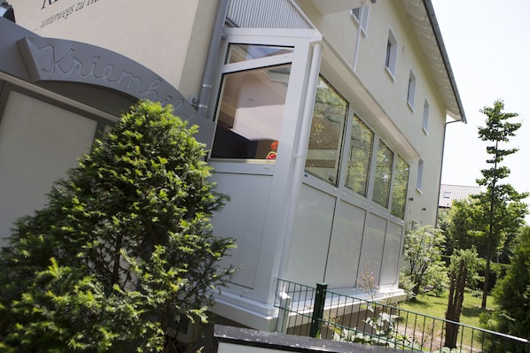 A building with a large window and a balcony. - Hotel Kriemhild am Hirschgarten (Munich)