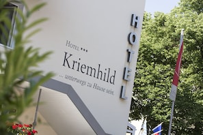 A sign for Hotel Krimhild with a modern design and a staircase leading to the entrance. - Hotel Kriemhild am Hirschgarten (Munich)