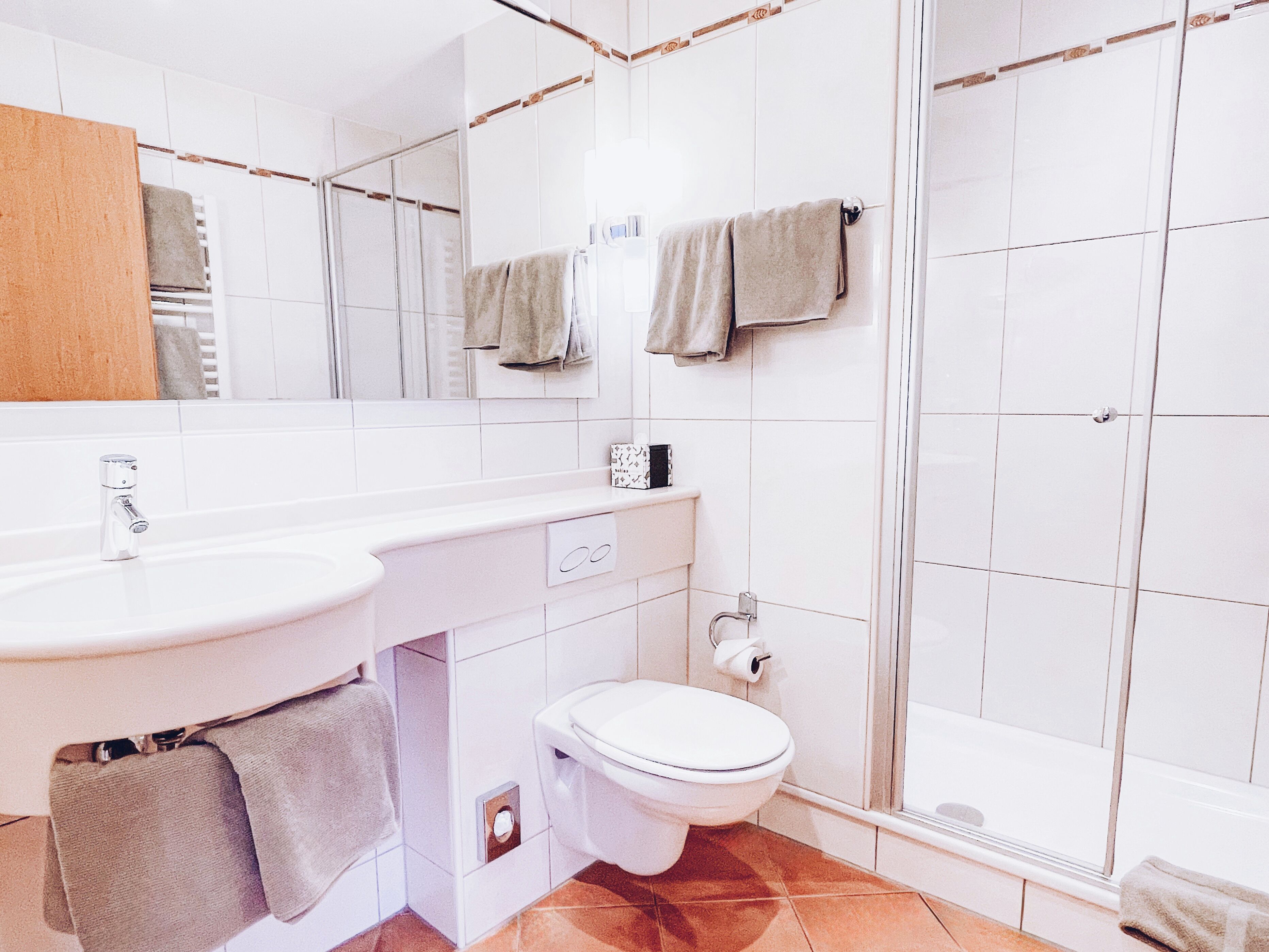 A modern bathroom with a white sink, toilet, and shower.