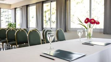 A conference room with a long table, chairs, a vase with flowers, and a glass of water.