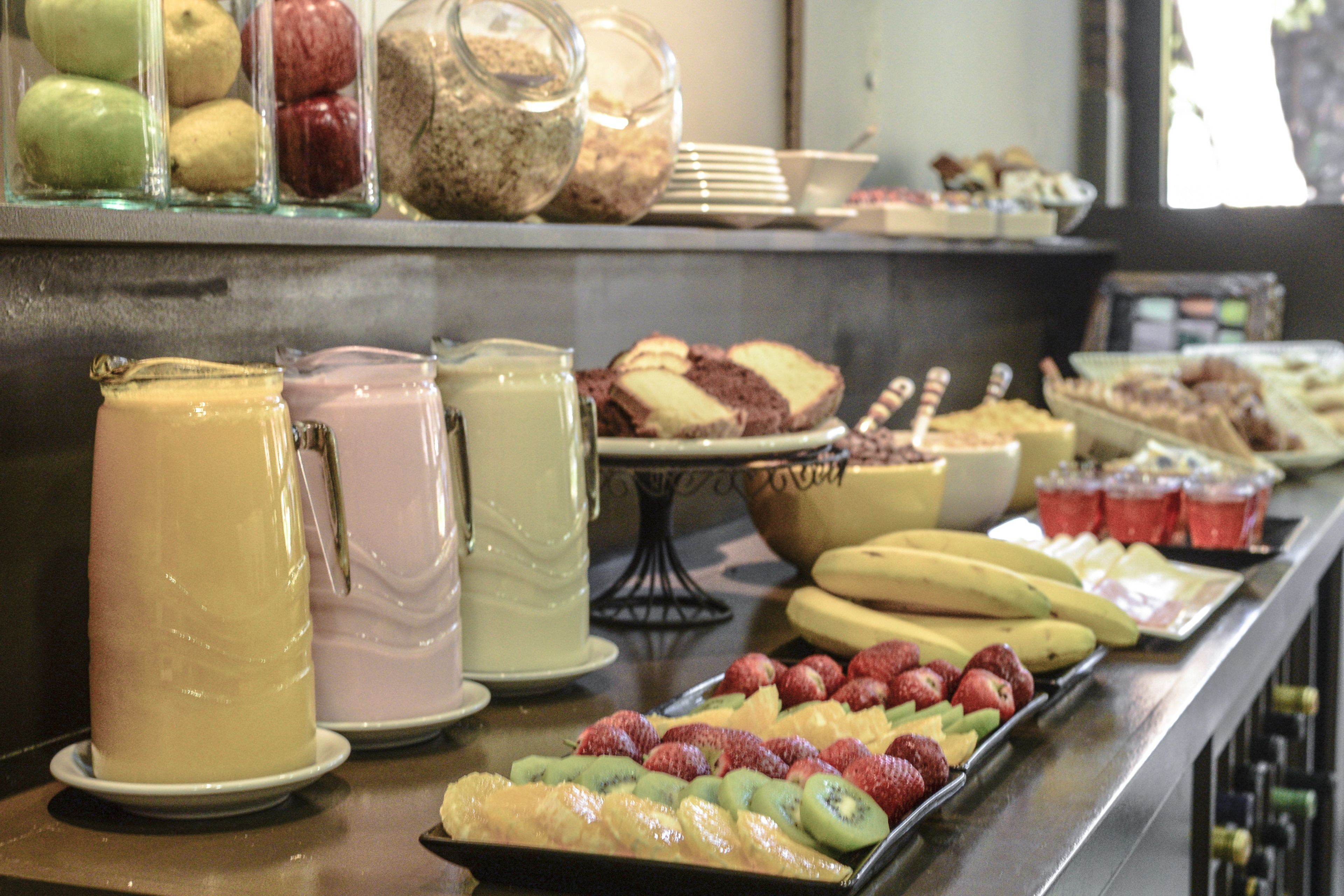 Un bufé con distintos alimentos, entre ellos frutas, pasteles y bebidas.