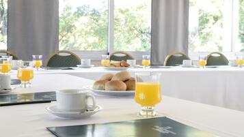 A breakfast table set with plates of pastries, glasses of orange juice, and a tablet.