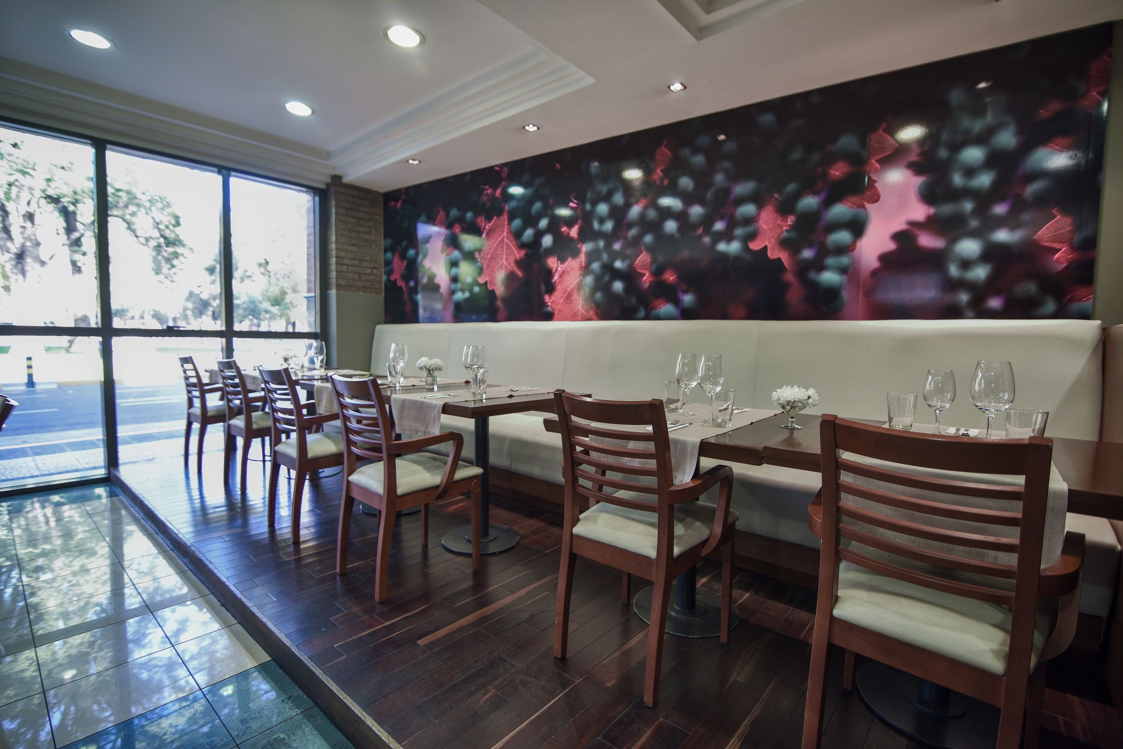 A restaurant with wooden chairs and tables, a large window, and a wall mural.