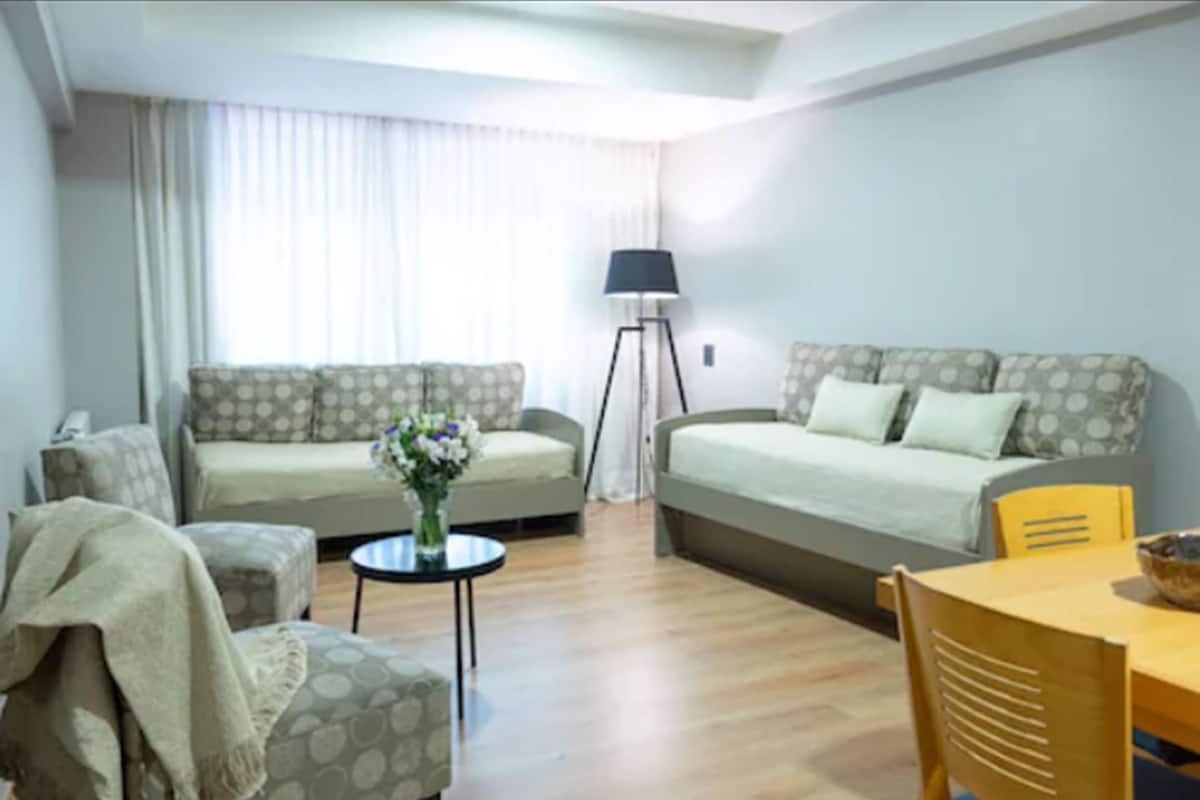Un salon avec deux canapés, une table basse, une lampe et une table à manger avec des chaises.
