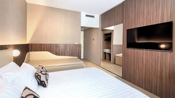 Une chambre d’hôtel équipée d’un lit, d’un téléviseur fixé au mur, d’un miroir et d’une armoire.
