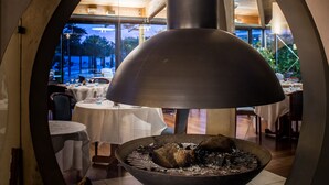A restaurant with a large, modern grill in the center, surrounded by tables and chairs. - Hotel Les Grenettes (Sainte-Marie-de-Re)